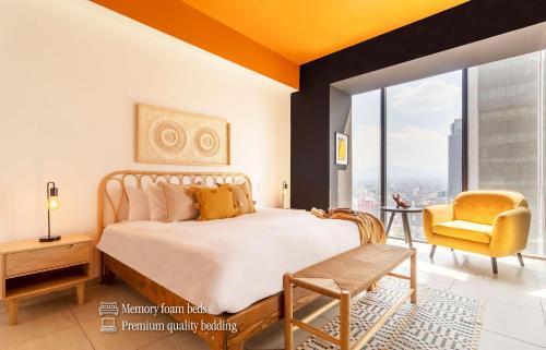a bedroom with a large bed and a yellow chair at Casa Magenta by Kukun in Mexico City