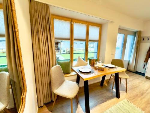 a dining room with a table and chairs and windows at Hirsere Studio 2 in Ursenbach