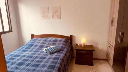 a small bedroom with a blue plaid bed with a night stand at Aconchego - com Garagem in Santa Maria