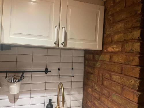 a kitchen with white cabinets and a brick wall at Skansen in Vilnius