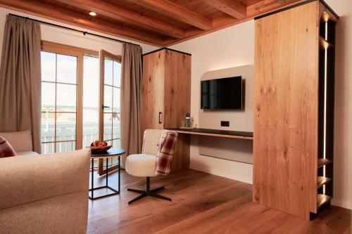 a room with a bed and a desk with a television at Landhotel Haringerhof mit Saunawelt und Naturbadeteich in Grafenhausen