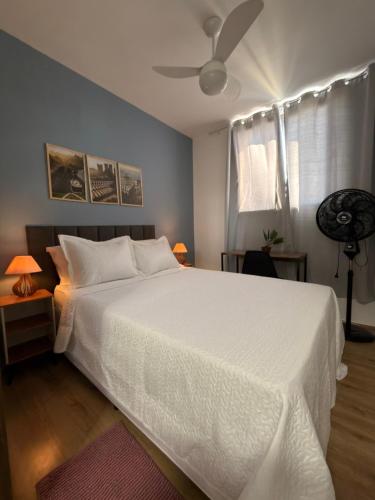 a bedroom with a white bed and a ceiling fan at Conforto e Localização perfeita Centro RJ 20 min Copacabana e Piscina in Rio de Janeiro