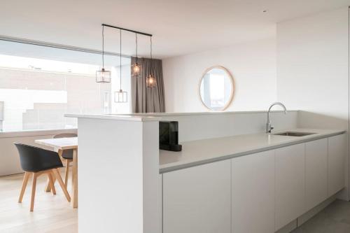 a white kitchen with a sink and a table at Skyline Flats Gent in Ghent