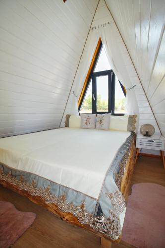 a bed in a white room with a window at Cabana Magia Apusenilor in Arada