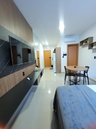 a bedroom with a bed and a table and a tv at Modern Studio 102 proximo Anashoping in Anápolis