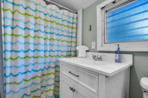 a bathroom with a sink and a shower curtain at Fast Wi-Fi | Linen & Towel | Coffee | Prof Cleaned in Seaside Park