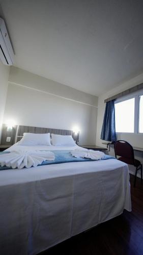 a large white bed in a room with a window at LH Plaza Hotel in Chapecó