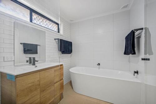 a white bathroom with a tub and a sink at Francis 31 in Port Macquarie
