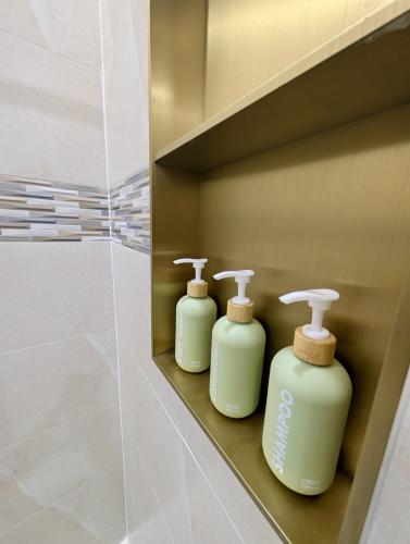 three green soap bottles sitting on a shelf in a bathroom at Salt & Breeze Villa in Priory