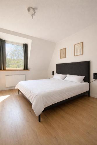 a bedroom with a large white bed with a window at Altbau Apartment mit toller Terrasse in Mülheim an der Ruhr