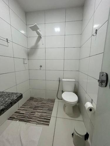 a bathroom with a toilet in a white tiled room at Aurora Serena - Casa com 2 quartos, próximo a rodoviária e aeroporto in Palmas