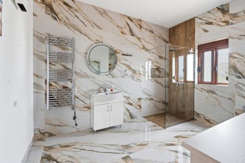 a bathroom with marble walls and a sink and a mirror at Vila Palma in Berat