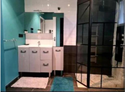 a bathroom with a white sink and a blue wall at Villa cosy in Biganos