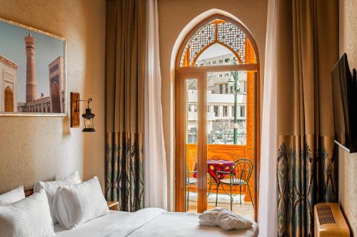 a bedroom with a bed and an open door to a balcony at Farovon Tashkent Boutique Hotel in Tashkent