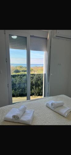 a bedroom with a bed with two towels and a window at Rados Villa Flora in Fažana