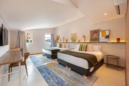 a bedroom with two beds and a desk and a tv at Medellinn The Blooming Hotel in Medellín