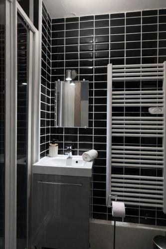 a black tiled bathroom with a sink and a mirror at Le Royal Colbert - Hyper Centre - Cozy & Elegant in Tours