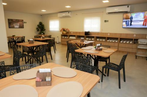 a dining room with tables and chairs and a screen at Hotel Jaiba Premium in Terra Fôfa