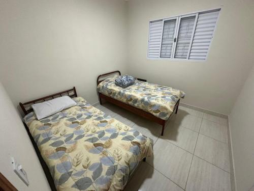 a bedroom with two beds and a window at Mar Azul in Espirito Santo Do Pinhal