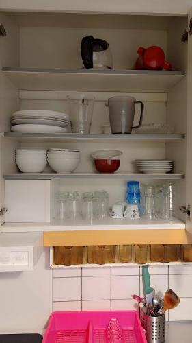 a kitchen shelf with dishes and bowls and utensils at Station Stay Örebro in Örebro