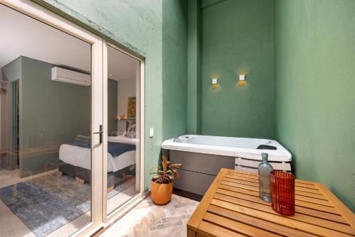 a room with a bath tub and a table with a window at Medellinn The Blooming Hotel in Medellín