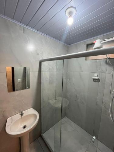 a bathroom with a glass shower and a sink at Hotel Avenida in Nova Friburgo