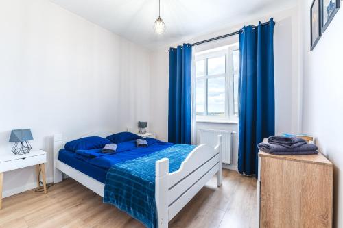 a bedroom with a bed with blue sheets and a window at Apartament Pirat in Ostróda