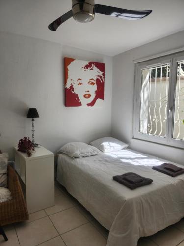 a white bedroom with a bed and a window at Chaleureux appartement in Nîmes