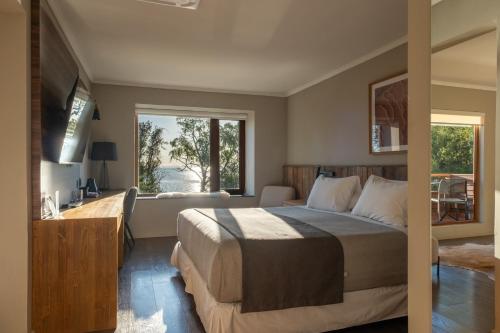 a bedroom with a bed and a desk and a window at Cascadas Hotel in Puerto Octay