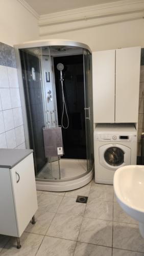 a bathroom with a shower and a washing machine at Szigetköz Győrzámoly Apartman in Győrzámoly