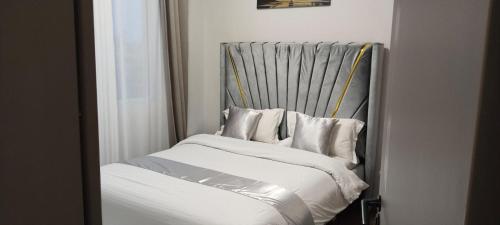 a bed with white sheets and pillows in a room at Sabaki's Homely One bedroom Apartment - Near JKIA, Airport in Marimbeti