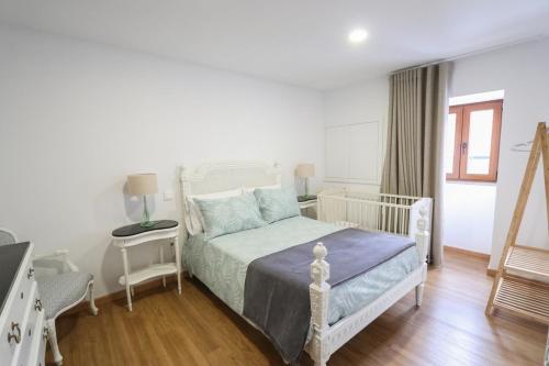 a bedroom with a bed and a table with a lamp at Casa da Madrinha - Paredes de Coura in Paredes de Coura