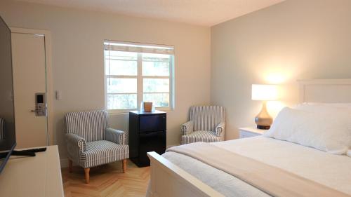 a bedroom with a bed and two chairs and a window at The Palm Rose in West Palm Beach