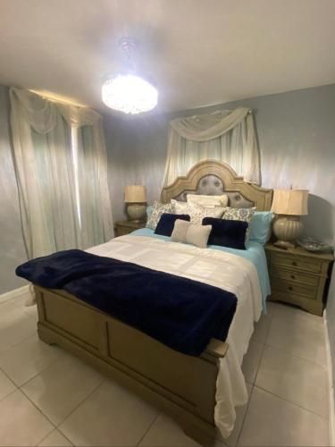 a bedroom with a large bed with blue sheets and pillows at Caribbean Staycation in Portmore