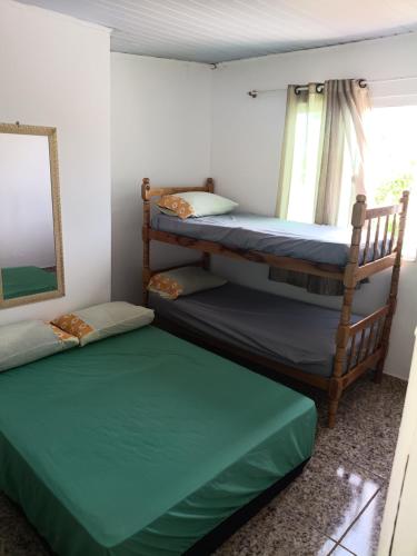 two bunk beds in a room with a window at Casa 70 Hostel 350m da praia Balneario Flamingo in Matinhos