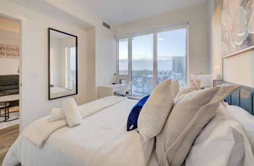 a bedroom with a large white bed with pillows at Modern & Stylish Condo Downtown KW in Kitchener