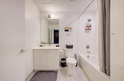 a white bathroom with a toilet and a sink and a tub at Modern & Stylish Condo Downtown KW in Kitchener