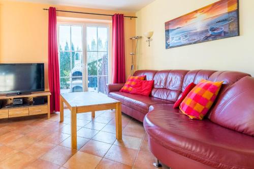 a living room with a leather couch and a television at Ferienhaus Mandy in Wohlenberg