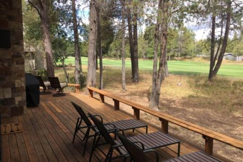 a deck with chairs and tables and a view of a golf course at 4 Spyglass Lane in Sunriver