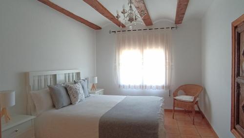 a white bedroom with a bed and a window at Casa Carmeta Beceite in Beceite