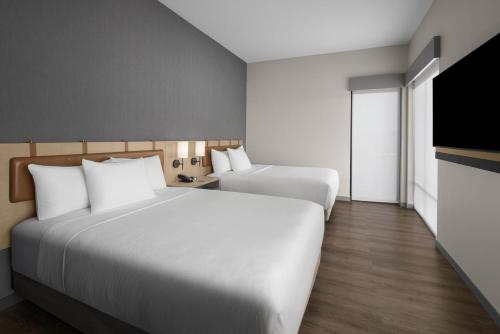 a hotel room with two beds and a flat screen tv at Hyatt Place Bozeman Yellowstone Airport in Belgrade