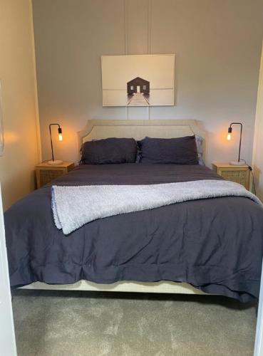 a bedroom with a large bed with blue sheets and two lamps at The Haven in Blackall