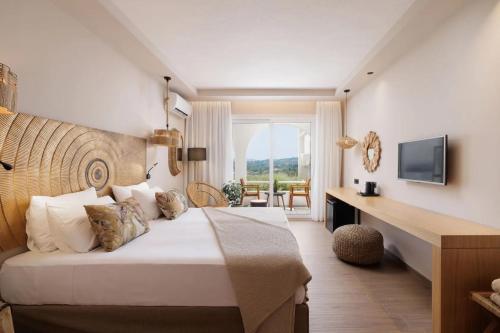 a bedroom with a bed and a desk and a television at Marilena Sea View Hotel in Pyrgi