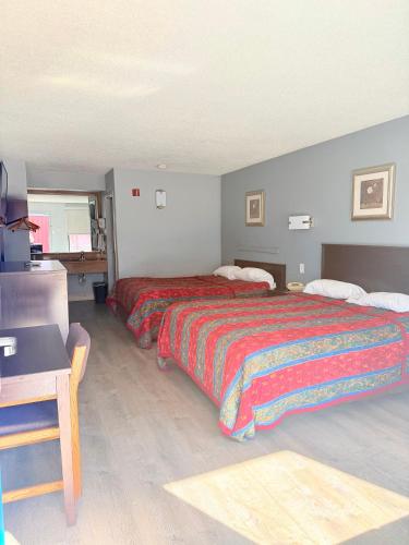 a hotel room with two beds and a desk at Knights Inn Ruther Glen in Ruther Glen