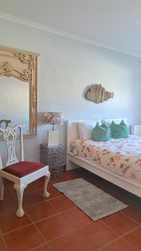 a bedroom with a bed and a mirror and a chair at Camarção Violante in Foz do Arelho