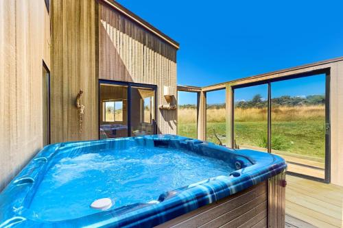a hot tub on a deck next to a house at West Meadow in Sea Ranch