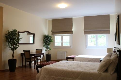 a bedroom with two beds and a table and a mirror at Villa São Carlos in Caxias do Sul