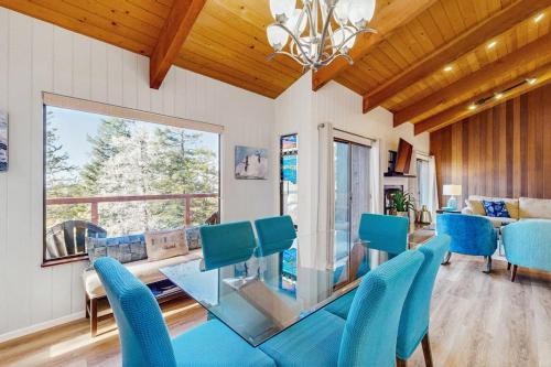 a dining room with a glass table and blue chairs at Sea Raven in Gualala