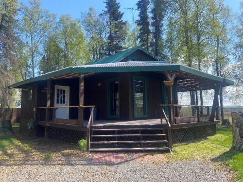 a small cabin with a green roof and a porch at Beaver Creek Hideaway in Kenai