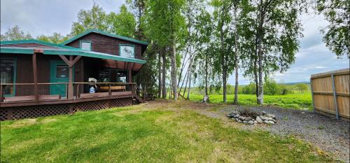 a cabin in the woods next to a yard at Beaver Creek Hideaway in Kenai